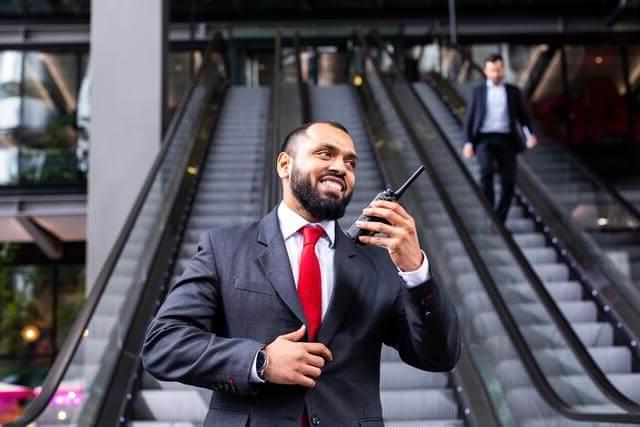 安全 guard using a radio, standing at the bottom of escalators